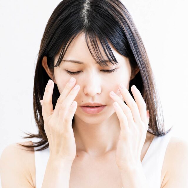 両頬に触れながら悩む女性の様子