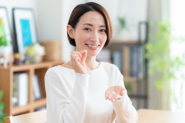 手に持った薬を口元に近づける40代女性