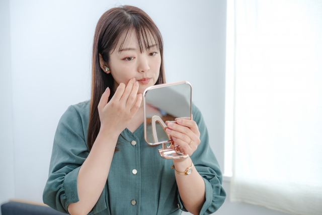 鏡を見ながら口元を気にする女性
